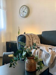 a clock on the wall above a table with a plant at Le 40 in LʼIsle-sur-la-Sorgue