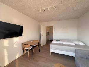 a bedroom with a bed and a table and a tv at AVANI Unnuisarfiit - Apartments in Umanak