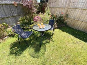 two chairs and a table with drinks on it in a yard at Daisy Cottage in Lymington