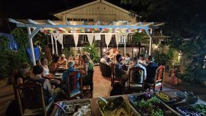 a group of people sitting at tables in a restaurant at night at Isano Nomad Hostel in Luang Prabang