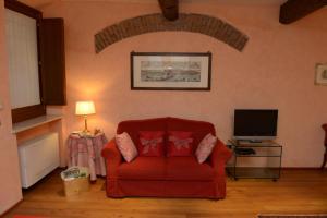 een woonkamer met een rode bank en een televisie bij La Cervetta in Mantova