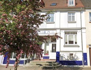 a white building with blue trim and a tree at Yutori - Apartment in Malchow