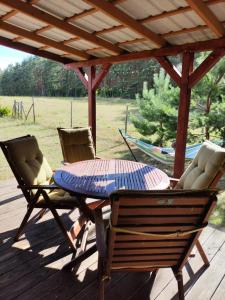 a patio table and chairs on a deck with a wooden roof at Agroturystyka Polana Harmonii in Przytoczna 