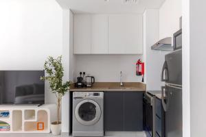a kitchen with a washing machine and a sink at Sahab - Urban Living 1BR by HA in Sharjah