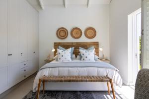 1 dormitorio con 1 cama con paredes blancas en Stableford Beachhouse Top Apartment, en Plettenberg Bay