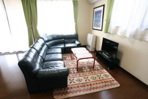 Una sala de estar con un sofá de cuero y una mesa. en Villa May Queen, en Fujikawaguchiko