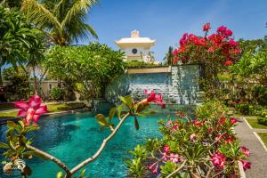 a swimming pool in front of a house with flowers at Rama Shinta Hotel Candidasa in Candidasa