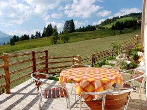 a table and chairs on a deck with a view of a hill at Apartments Serghela in San Cassiano