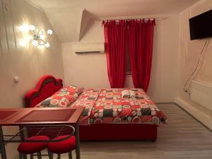a bedroom with a bed and a desk and red curtains at Apartman BAHUS Vrdnik in Vrdnik