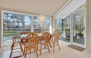 a dining room with a table and chairs and windows at Stunning Home In Sjællands Odde in Yderby