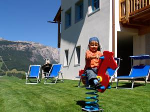 un niño pequeño sentado en un caballo de juguete en un patio de recreo en Apartments Serghela, en San Cassiano