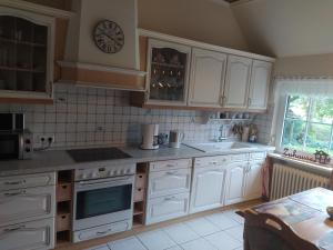 una cucina con armadi bianchi e un orologio sul muro di Mooroase Bauerngarten Ovelgönne a Ovelgönne