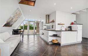 a kitchen with white cabinets and a living room at Holiday Home Marievænget in Tørresø