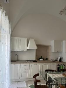 a kitchen with white cabinets and a table with chairs at La casa di Babele in Martina Franca