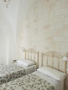 Dos camas en una habitación con una pared de ladrillo. en La casa di Babele, en Martina Franca