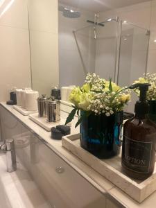 un bancone del bagno con una bottiglia di crema e fiori di Suite3, 7 min walk from Opera or Lake a Zurigo