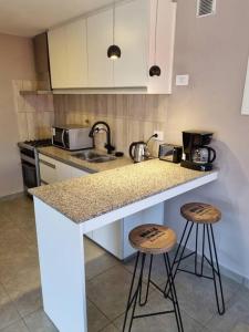 een keuken met 2 barkrukken en een aanrecht bij Moderno Duplex 1 - Complejo Las Cerezas in Esquel