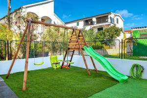 une aire de jeux avec un toboggan et des balançoires dans l'établissement Apartments Sunny Sky, à Vodice