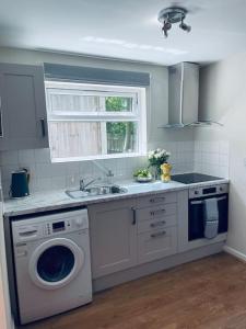 a kitchen with a washing machine and a sink at Ivy Cottage Two Bedroom & Garden in Temple Fortune in London
