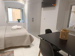 a white room with a bed and a desk and a window at Tatiana's Town Studio in Corfu