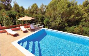 a blue swimming pool with chairs and an umbrella at Holiday Home Smokvica Smokvica in Smokvica