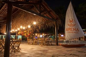 an outdoor patio with tables and chairs at night at Arena Carneiros Hotel by AFT in Tamandaré