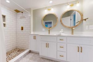 a white bathroom with two mirrors and a sink at 126 Grand Pavilion in Isle of Palms +18 photos