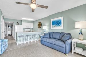 a living room with a blue couch and a kitchen at Royal Palms 907 in Gulf Shores