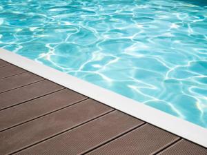 a pool with a wooden deck and blue water at La Bastide De Sauvetas in Bonlieu-sur-Roubion