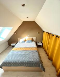 a attic bedroom with a bed and yellow curtains at Mesnil brayon in Neufchâtel-en-Bray +8 photos