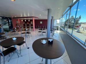 a restaurant with tables and chairs and windows at Hotel Caçula Do Pampa in São Gabriel