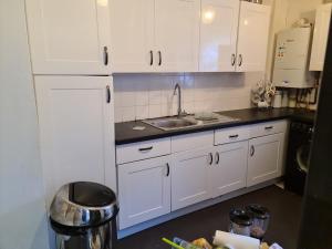 a kitchen with white cabinets and a sink at 669 London Road Wilmorton in Derby