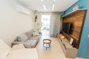 a living room with a couch and a tv at Conforto à beira-mar in Florianópolis