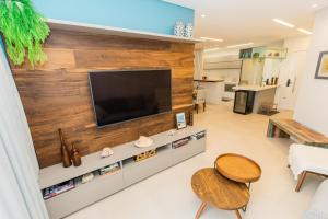 a living room with a large wooden wall with a flat screen tv at Conforto à beira-mar in Florianópolis