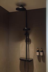 a shower in a bathroom with two bottles on the wall at Addostays - Mori Machiya in Bandung