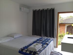 a bedroom with a white bed with a window at STUDIO KITSOSSEGO in Curitiba