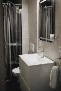 a bathroom with a sink and a toilet and a mirror at Guesthouse Lyngholt in Þórshöfn