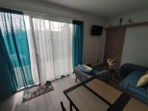 a living room with a couch and two large windows at Logement proche Caen et plages in Colombelles