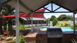 a barbecue under a pavilion next to a pool at Culcairn Motor Inn in Culcairn