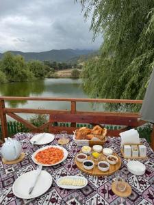 a picnic table with food and a view of a river at Chadir yurd glamp in İsmayıllı