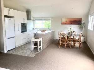 a kitchen with white cabinets and a table and chairs at Shearer's Quarters in Rotorua