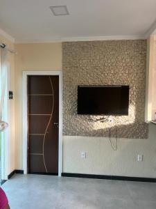 a living room with a television on a brick wall at Casa do Campinho in Marau