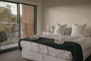 une chambre avec un grand lit avec des serviettes dessus dans l'établissement The Tides, à Coles Bay