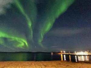 an image of the northern lights over a beach at Cave apartment in Þórshöfn