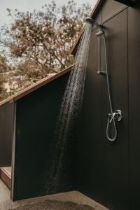 une douche avec de l'eau sortant du côté d'un bâtiment dans l'établissement The Tides, à Coles Bay