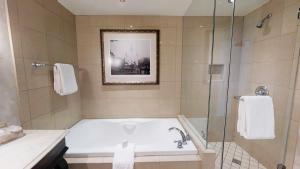 a bathroom with a tub and a glass shower at Harrah's New Orleans Hotel & Casino - A Caesars Rewards Destination in New Orleans