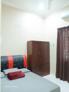 a bedroom with a bed and a wooden cabinet at Wardah Homestay Machang in Machang