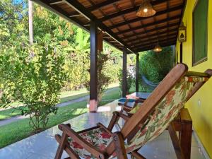 einen Schaukelstuhl auf einer Veranda mit einem Tisch in der Unterkunft Casa Toque das Bromélias in São Miguel dos Milagres