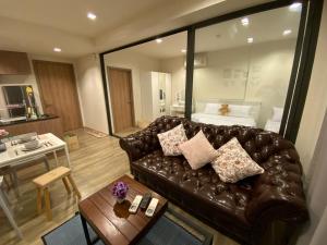 Una sala de estar con un sofá de cuero y una mesa. en Rain Cha-am Huahin, en Cha Am