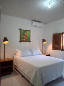 ein Schlafzimmer mit einem weißen Bett und zwei Lampen in der Unterkunft Casa Toque das Bromélias in São Miguel dos Milagres